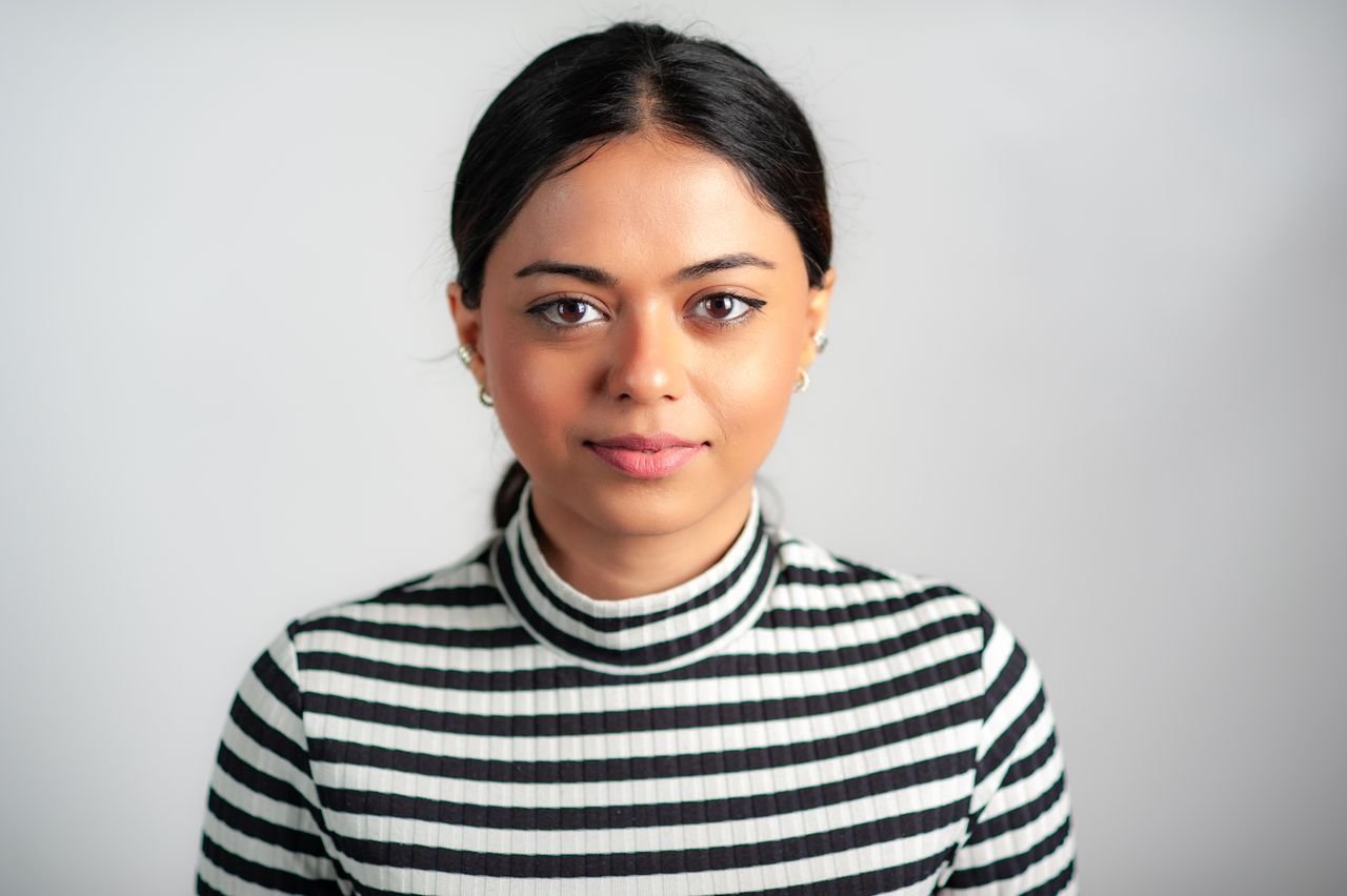 Elegant portrait of an adult woman in a striped turtleneck against a white background.